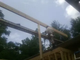 Carpenter setting a ridge beam over a new addition frame — Ice Dam Removal by Roofing Brothers in Footville