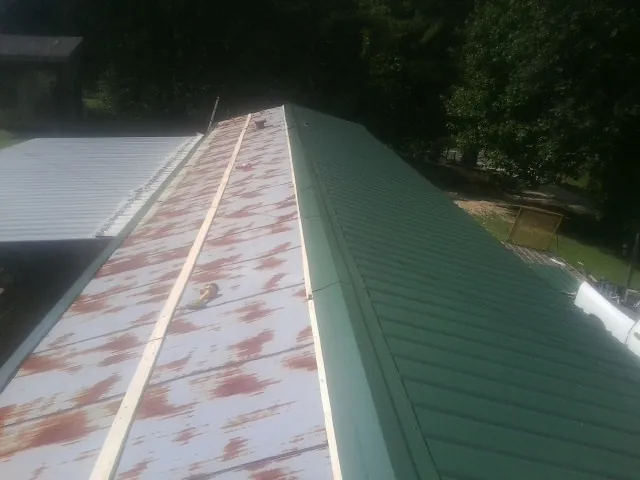 Old rusted panels beside newly installed green metal roofing — Wind Damage Roof Repair by Roofing Brothers in Footville