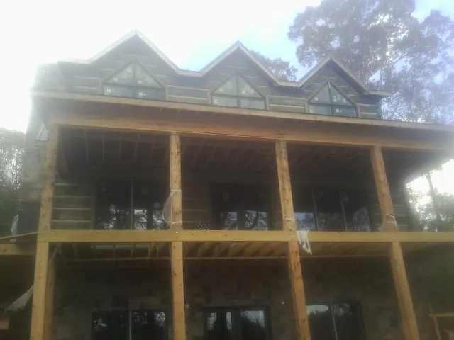 Dormers and porch framing on a large log home under construction — Roof Coating work by our crew in Footville