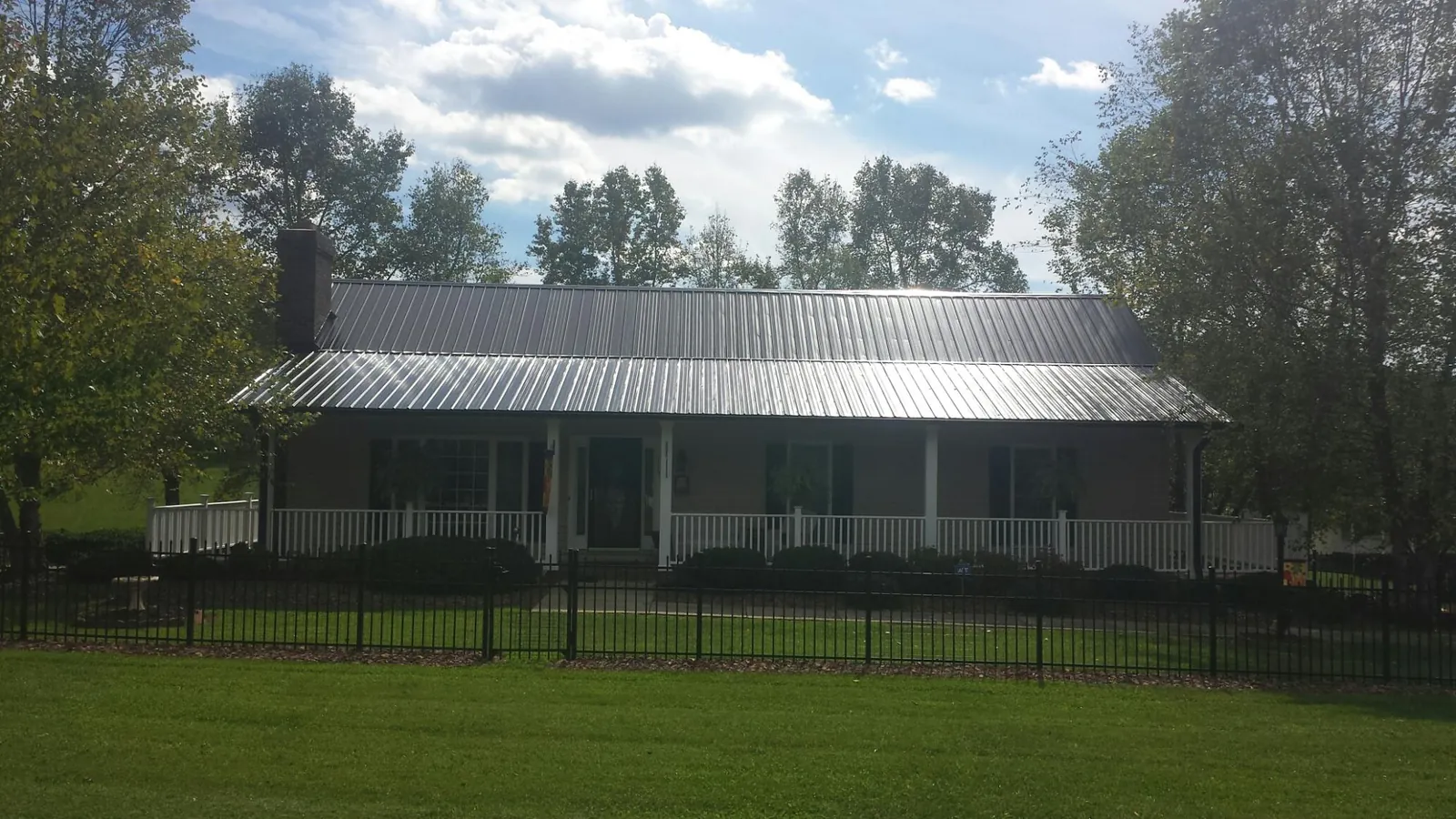 Gray metal roof on a brick ranch with a full width front porch — Gutter Guard Installation work by our crew in Footville