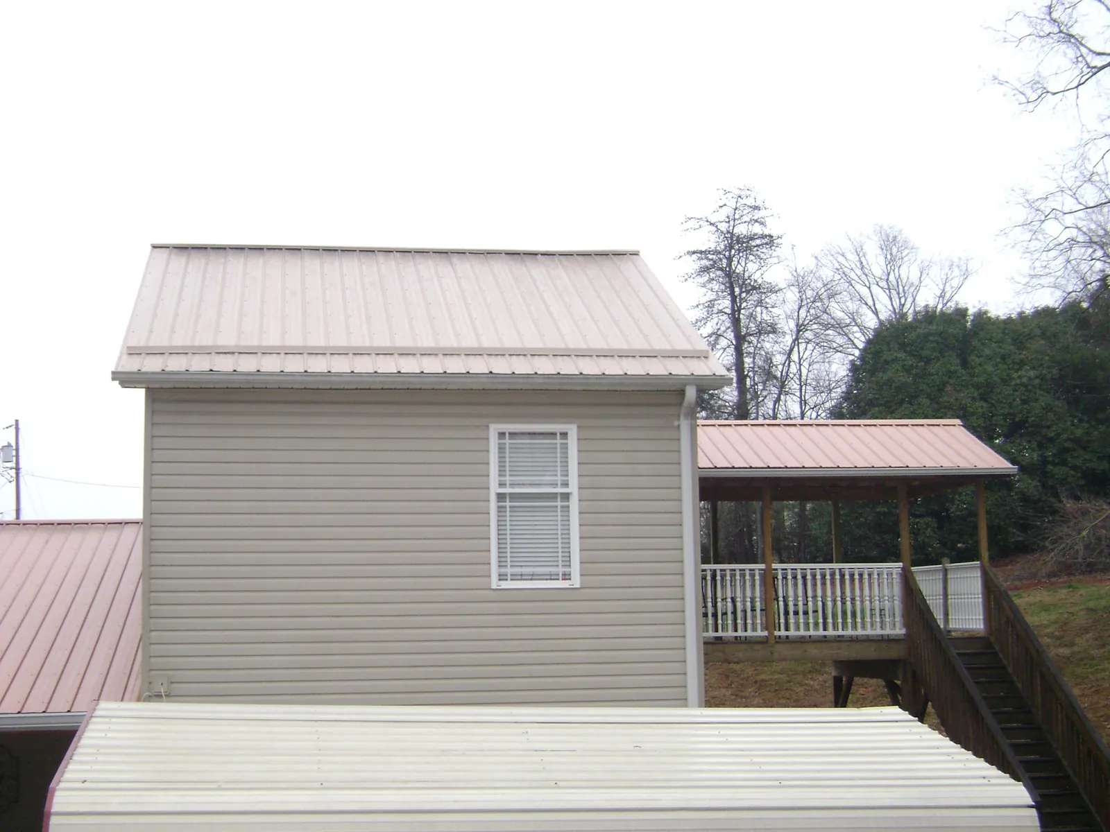 Tan metal roofs on a two story addition and attached porch, from a Roof Replacement job in Footville