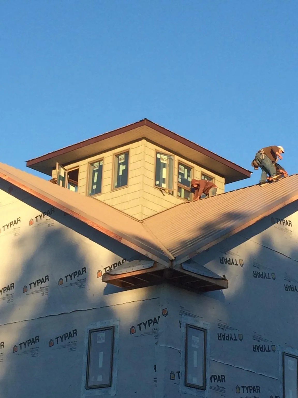 Roofers working around a rooftop cupola on a new metal roof at sunset — Roof Waterproofing in Footville by Roofing Brothers